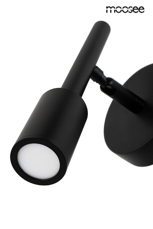 Czarny kinkiet LED Prisma 1-punktowy, z cylindryczną głowicą o białym kloszu, zamontowany na okrągłej podstawie. Ujęcie z boku, ukazujące prostą formę i możliwość regulacji kąta świecenia.