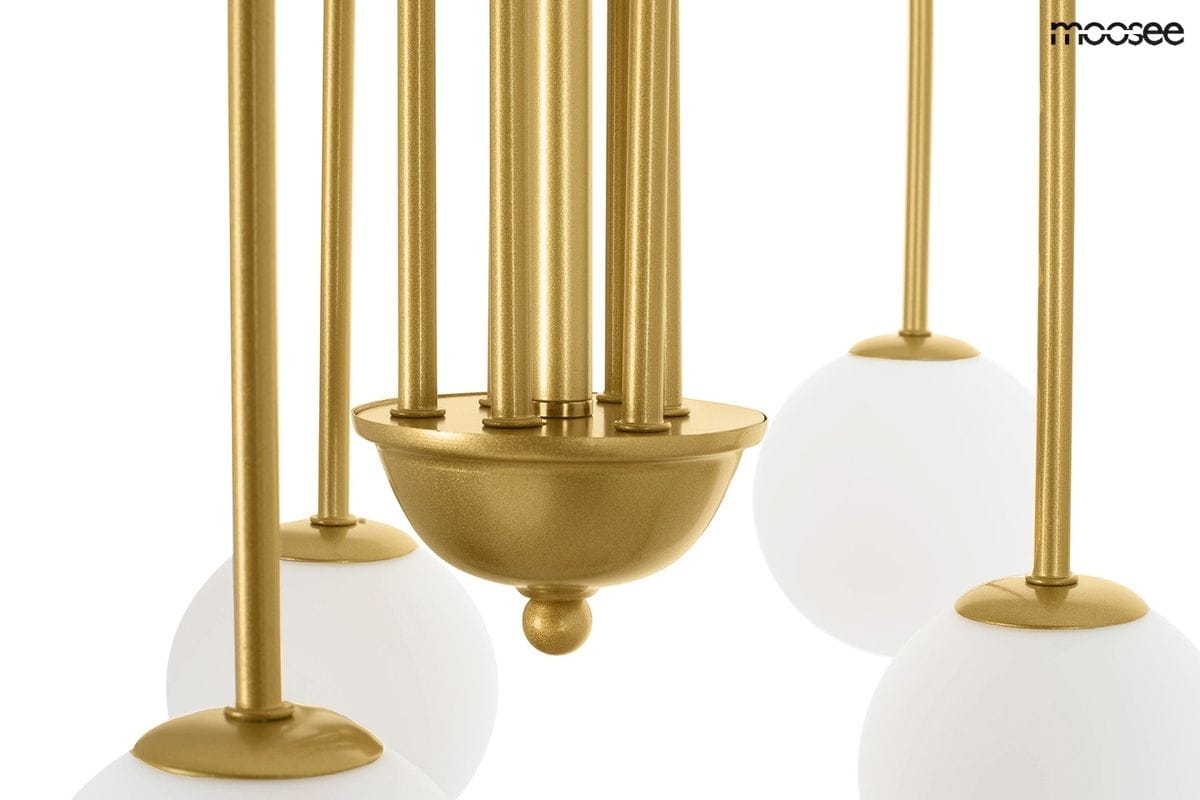 Złota lampa wisząca Neri z sześcioma punktami świetlnymi. Metalowa konstrukcja z okrągłymi, białymi kloszami. Ujęcie z bliska na detale mocowania i wykończenia.
