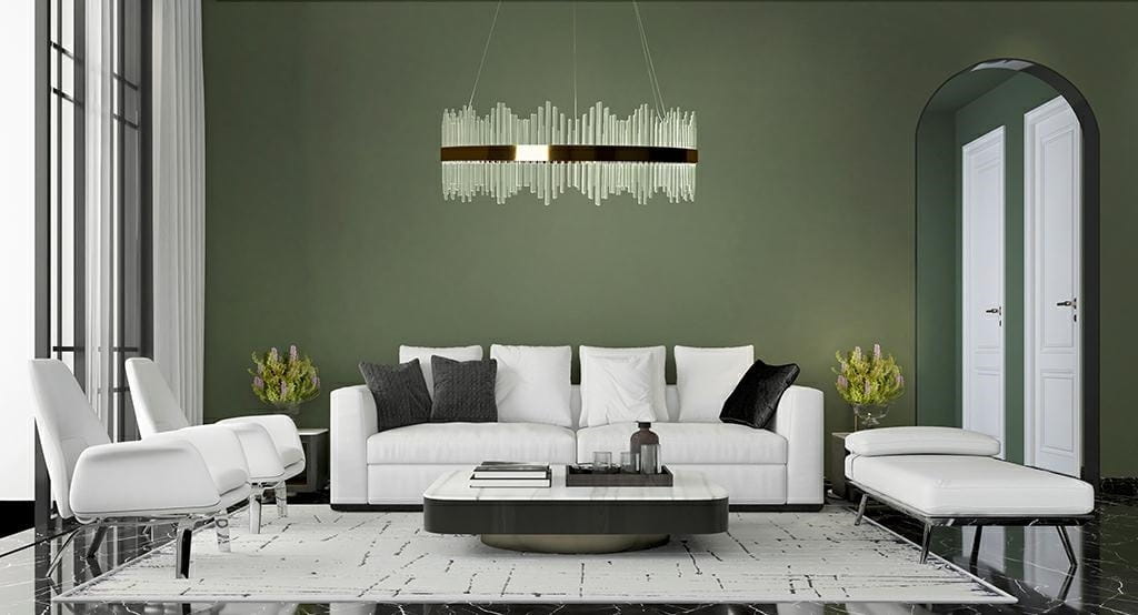 Złota lampa wisząca Florens 80 LED z przezroczystymi elementami, umieszczona nad białą sofą w nowoczesnym salonie. Lampa ma prostą, elegancką formę z metalowym akcentem, zawieszona na cienkim przewodzie w otoczeniu ciemnozielonej ściany.