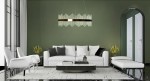 Złota lampa wisząca Florens 80 LED z przezroczystymi elementami, umieszczona nad białą sofą w nowoczesnym salonie. Lampa ma prostą, elegancką formę z metalowym akcentem, zawieszona na cienkim przewodzie w otoczeniu ciemnozielonej ściany.