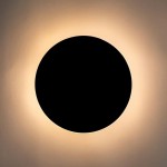 Kinkiet Shadow Sun 25 w kolorze czarnym, z okrągłym, matowym źródłem światła. Oświetlenie emituje ciepłe światło wokół ciemnej, centralnej tarczy. Zainstalowany na ścianie, prezentuje minimalistyczny design.