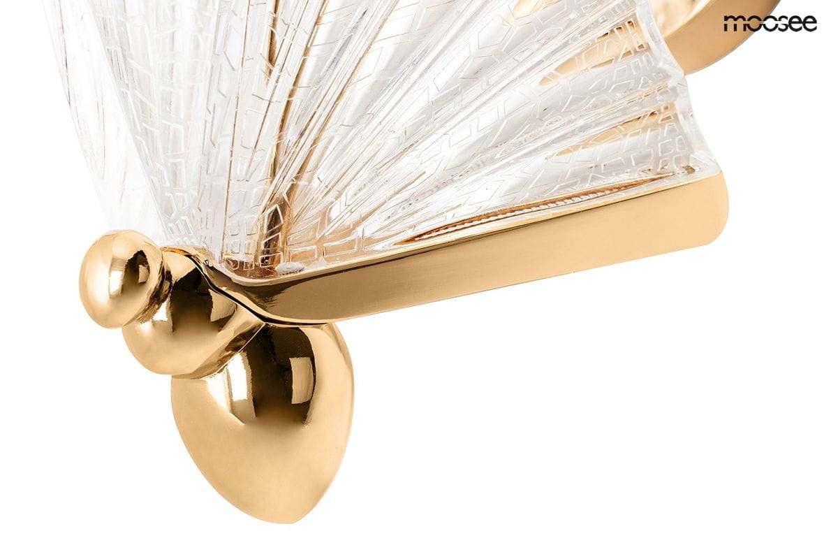 Kinkiet Butterfly S LED w kolorze złotym, z przezroczystą, teksturowaną kloszem w kształcie wachlarza. Złote mocowanie z okrągłym detalem. Ujęcie z boku, pokazujące detale konstrukcji i fakturę klosza.