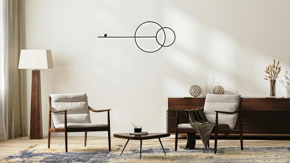 Czarna lampa wisząca LED Rage z trzema punktami świetlnymi, zawieszona w minimalistycznym wnętrzu. Lampa ma formę prostokąta z okręgami, umieszczona nad niskim, okrągłym stołem. Otoczenie to nowoczesny salon z drewnianymi meblami i jasnymi akcentami.