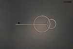 Czarna lampa wisząca Rage LED o trzech punktach świetlnych, z geometrycznymi kształtami: długi poziomy element oraz dwa okręgi, zawieszona na cienkich linkach. Tło jasnoszare, minimalistyczne, podkreślające nowoczesny design.