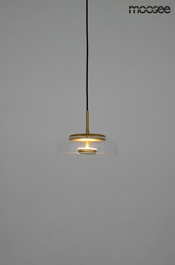 Złota lampa wisząca Eden LED z przezroczystym kloszem, pojedyncza, zawieszona na cienkim czarnym przewodzie. Widoczna źródło światła w centralnej części klosza, o minimalistycznym designie. Tło jednolite, szare.