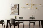 Złota lampa wisząca Piazetta LED, 6-punktowa, z okrągłymi kloszami, zawieszona nad stołem w jadalni. W tle abstrakcyjny obraz oraz roślina doniczkowa. Nowoczesny design, minimalistyczna aranżacja.