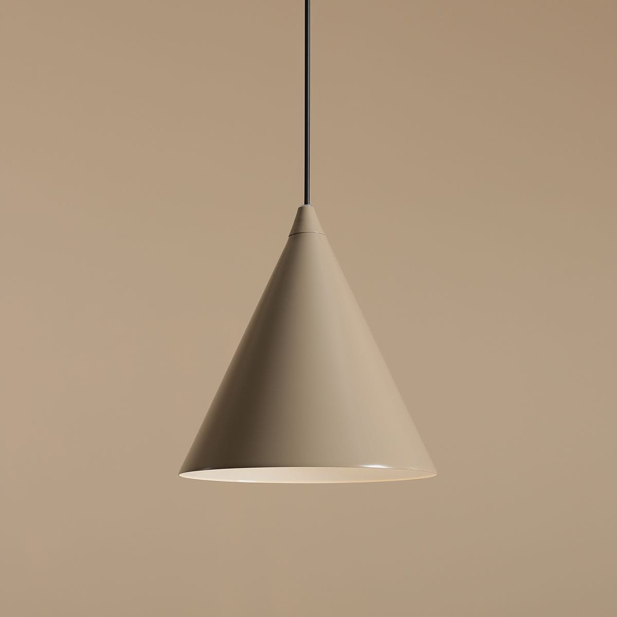 Lampa wisząca Form Beige 1-punktowa o kształcie stożka, w kolorze beżowym, zawieszona na cienkim, czarnym przewodzie. Tło w odcieniu beżowym, podkreślające minimalistyczny design lampy.