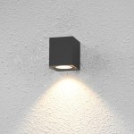 Kinkiet elewacyjny Genta OWL-2197-1SQ w kolorze czarnym, o prostokątnym kształcie, zamontowany na szarej ścianie. Emituje światło skierowane w dół, podkreślając teksturę ściany.