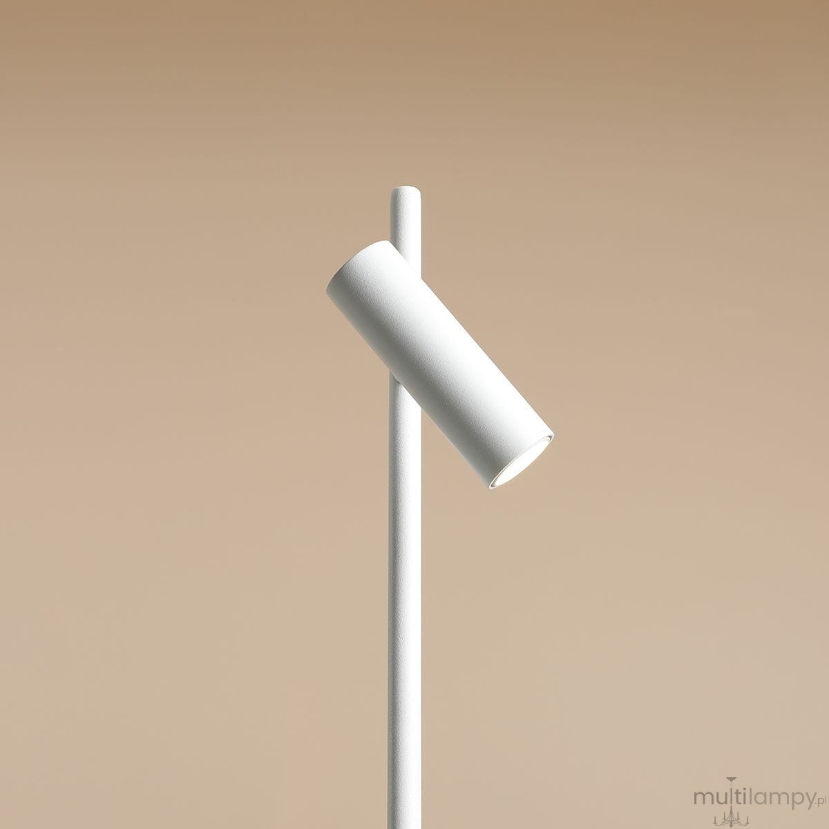 Lampka biurkowa Trevo w kolorze białym, z cylindryczną głowicą skierowaną pod kątem, zamontowaną na smukłym, prostym stelażu. Produkt ma minimalistyczny design, umieszczony na jednolitym tle w neutralnym odcieniu.