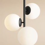 Lampa sufitowa 3-punktowa Fin M w kolorze czarnym. Składa się z trzech białych, kulistych kloszy zamocowanych na czarnym stelażu. Ujęcie z góry, ukazujące detale mocowania i kształt kloszy. Tło w jasnym, neutralnym odcieniu.
