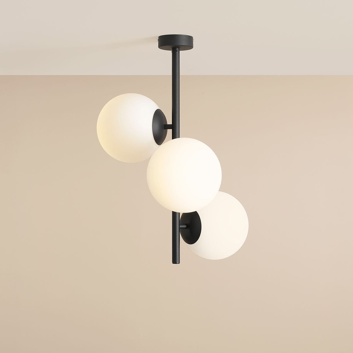 Czarna lampa sufitowa Fin M z trzema okrągłymi kloszami w kolorze białym, zamontowana na prostym, metalowym stelażu. Klosze są rozmieszczone nieregularnie, co nadaje nowoczesny wygląd. Ujęcie z góry, na jednolitym tle.