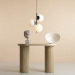 Lampa wisząca Fin M 3-punktowa w kolorze czarnym, z trzema okrągłymi, matowymi kloszami w kolorze białym. Zawieszona nad stołem z kolumnami, w minimalistycznym otoczeniu. Tło w delikatnym odcieniu beżu.