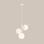 Lampa wisząca Fin M z trzema okrągłymi, białymi kloszami. Klosze umieszczone na smukłym, białym stelażu, zwisają na cienkim przewodzie. Prosta forma, nowoczesny design, zawieszona centralnie w jasnym tle.