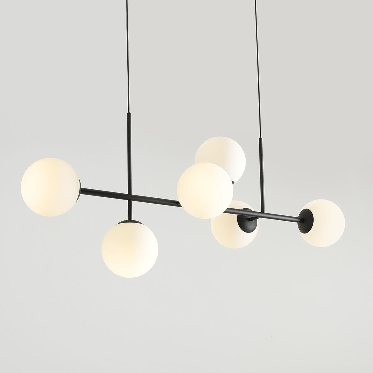 Lampa wisząca Fin 6-punktowa w kolorze czarnym. Konstrukcja z metalowymi rurkami z sześcioma okrągłymi, mlecznobiałymi kloszami. Zawieszona na dwóch cienkich linkach, w minimalistycznym stylu, idealna do nowoczesnych wnętrz.