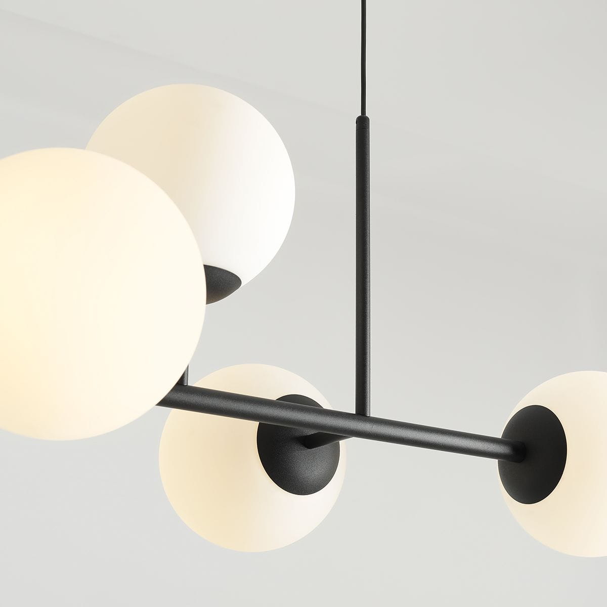 Lampa wisząca Fin 6-punktowa, czarna. Składa się z sześciu białych, okrągłych kloszy umieszczonych na czarnych metalowych ramionach. Ujęcie z góry, pokazujące detale konstrukcji i połączeń. Tło jasne, minimalistyczne.