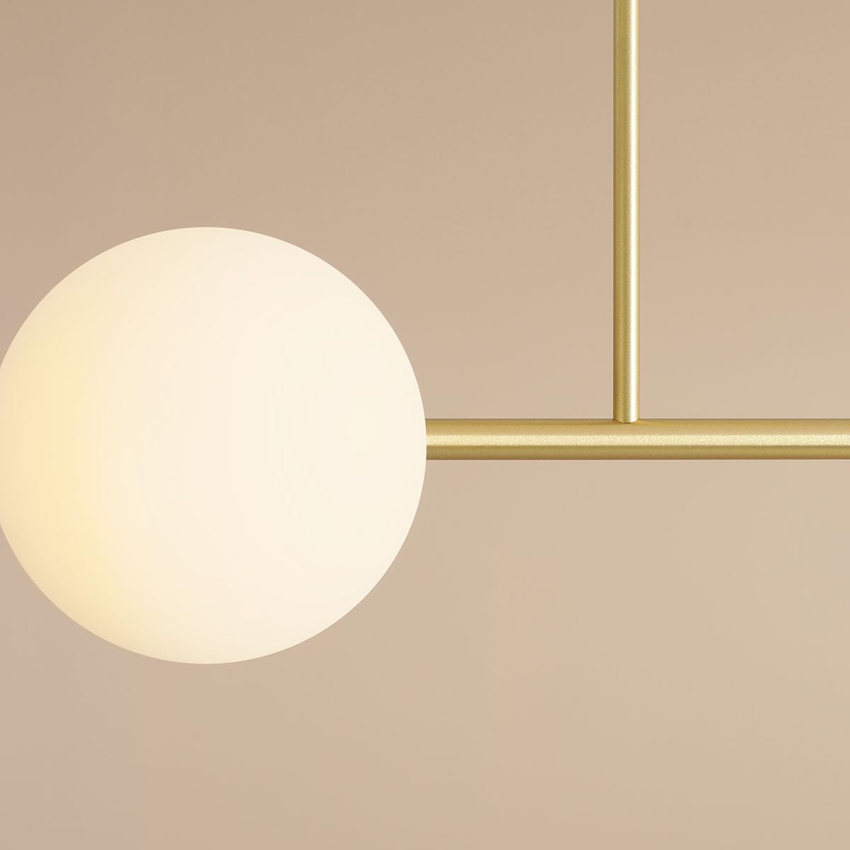 Lampa sufitowa Dione w kolorze mosiądzu z czterema punktami świetlnymi, z zaokrąglonym, białym kloszem ze szkła. Produkt zamontowany na prostym, metalowym stelażu, widoczny z bliska, na jednolitym tle.