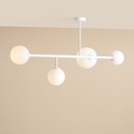 Lampa sufitowa Dione w kolorze białym, z czterema okrągłymi kloszami w matowym wykończeniu. Ułożona poziomo, z centralnym mocowaniem do sufitu. Klosze umieszczone na dwóch poziomach, co nadaje nowoczesny wygląd. Tło w neutralnym odcieniu.