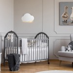 Biały kinkiet w kształcie chmurki, montowany na ścianie, emitujący delikatne światło. Znajduje się nad łóżeczkiem dziecięcym w jasnym, minimalistycznym wnętrzu. Tło w neutralnych kolorach, z elementami dekoracyjnymi.