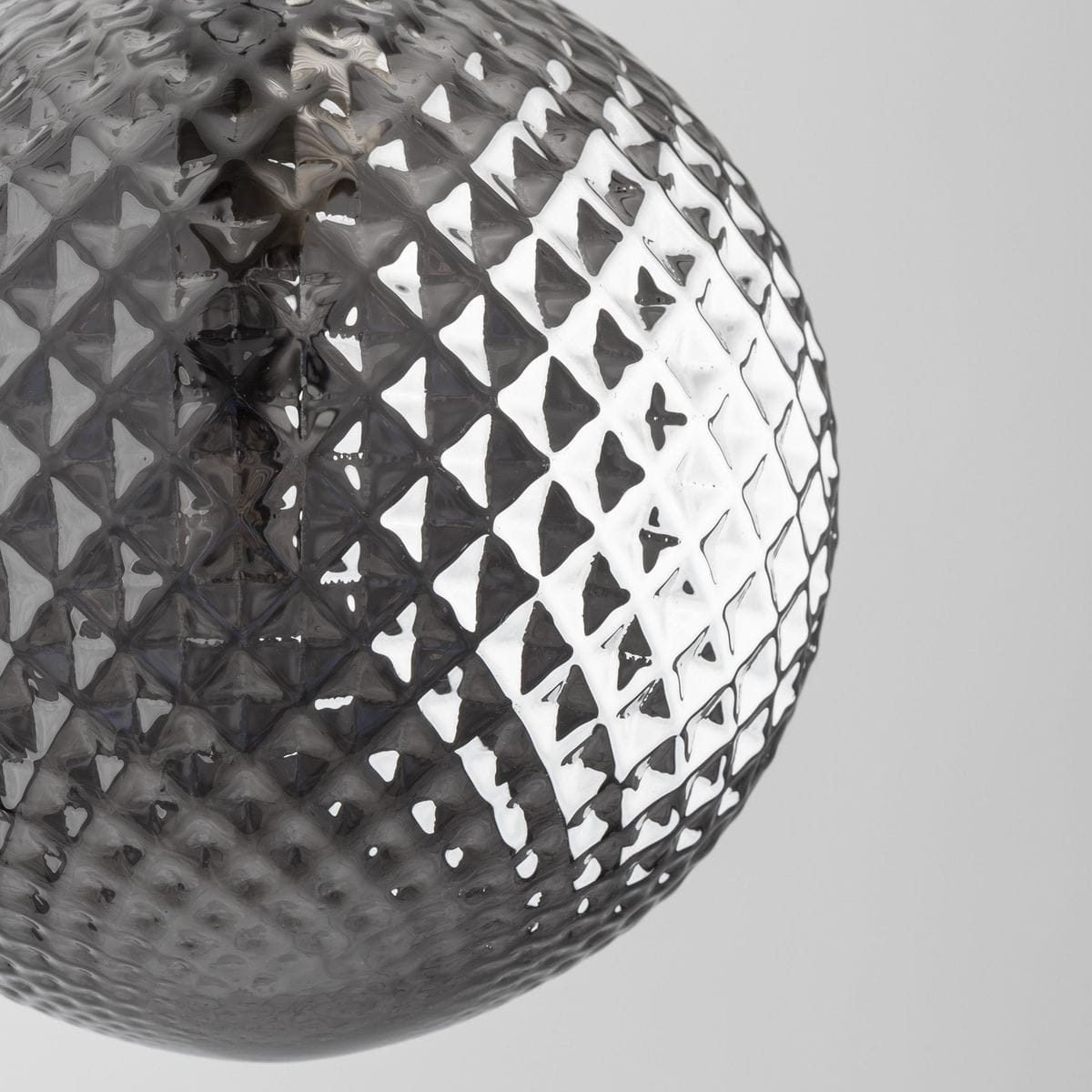 Czarna lampa wisząca Elena z 1 punktem świetlnym, wykonana z przezroczystego szkła z geometrycznym wzorem w formie diamentów. Ujęcie z bliska na klosz, ukazujące detal i fakturę. Tło jasne, minimalistyczne.