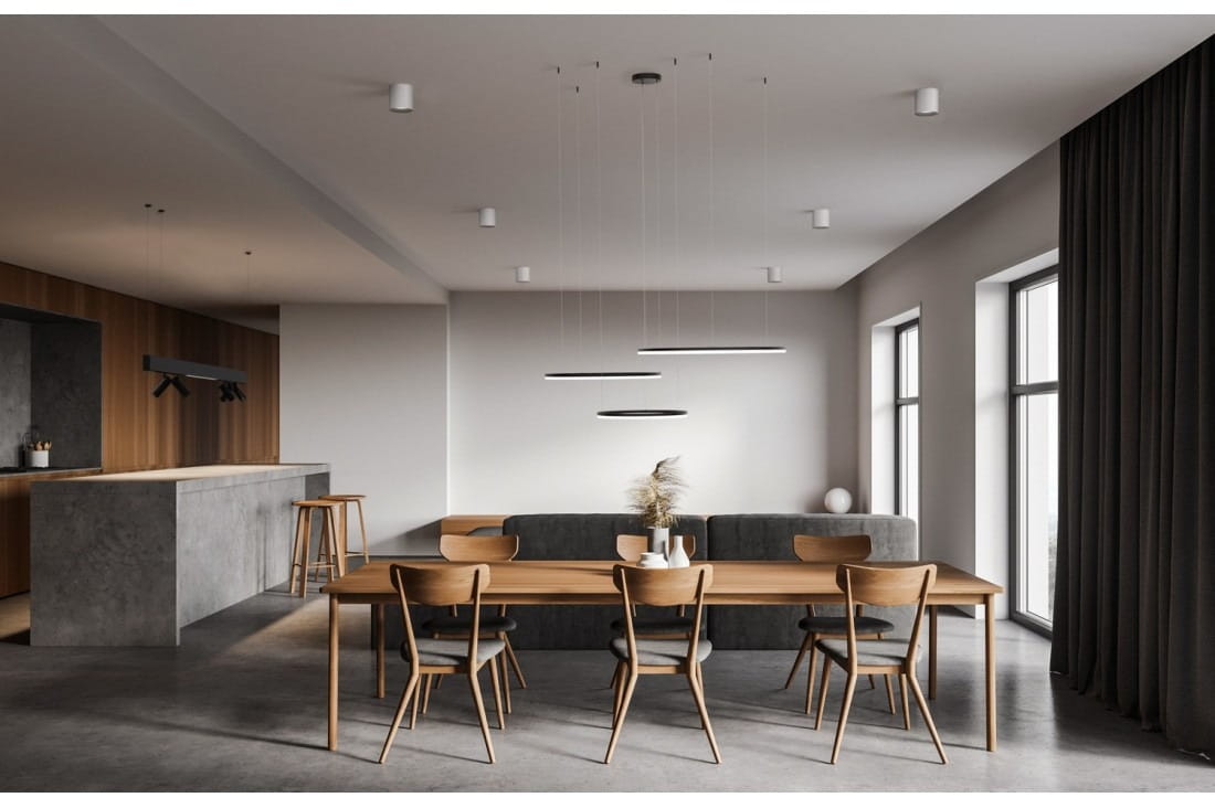 Czarna lampa wisząca LED Halo 100+80+60 z trzema punktami świetlnymi, zawieszona nad drewnianym stołem w nowoczesnej jadalni. W tle widoczne okna i zasłony, a także elementy kuchenne w stylu minimalistycznym.