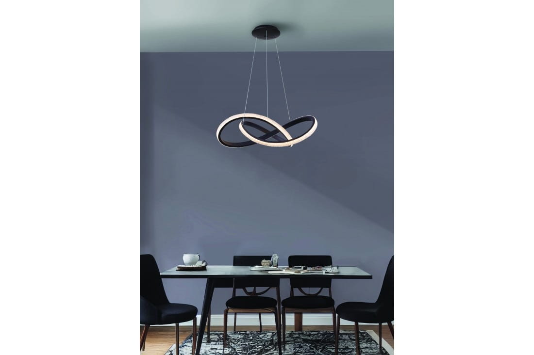 Czarna lampa wisząca Infinity D80 LED z pilotem, zawieszona nad stołem. Składa się z dwóch splątanych pierścieni, jeden błyszczący, drugi matowy. Tło w stonowanej szarości, na stole widoczne filiżanki i talerze.