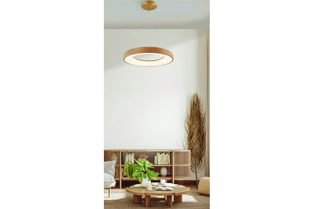 Lampa wisząca Santana D60 w kolorze drewna, z okrągłym kloszem LED, regulowana w zakresie 3000-6500K. Zawieszona na cienkim przewodzie, w jasnym wnętrzu z drewnianymi meblami i roślinami. Widoczny pilot do sterowania.