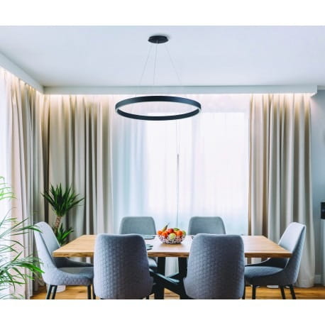 Czarna lampa wisząca Marco D100 LED o regulowanej temperaturze barwowej 3000-6500K, zawieszona nad drewnianym stołem w jadalni. W tle zasłony i roślina, ustawiona w nowoczesnej aranżacji.