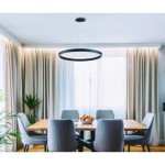 Czarna lampa wisząca Marco D100 LED o regulowanej temperaturze barwowej 3000-6500K, zawieszona nad drewnianym stołem w jadalni. W tle zasłony i roślina, ustawiona w nowoczesnej aranżacji.