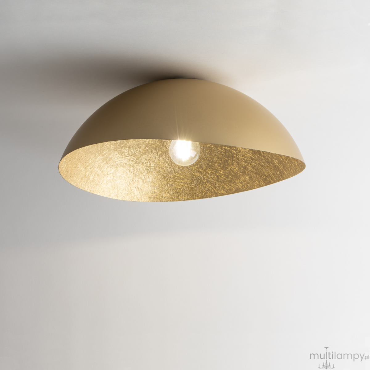 Lampa sufitowa Solaris S w kolorze złotym, 1-punktowa, z półkolistym kloszem o matowej powierzchni zewnętrznej i błyszczącym wnętrzem. Widoczna żarówka w centralnej części, montowana do sufitu. Tło jasne, minimalistyczne.