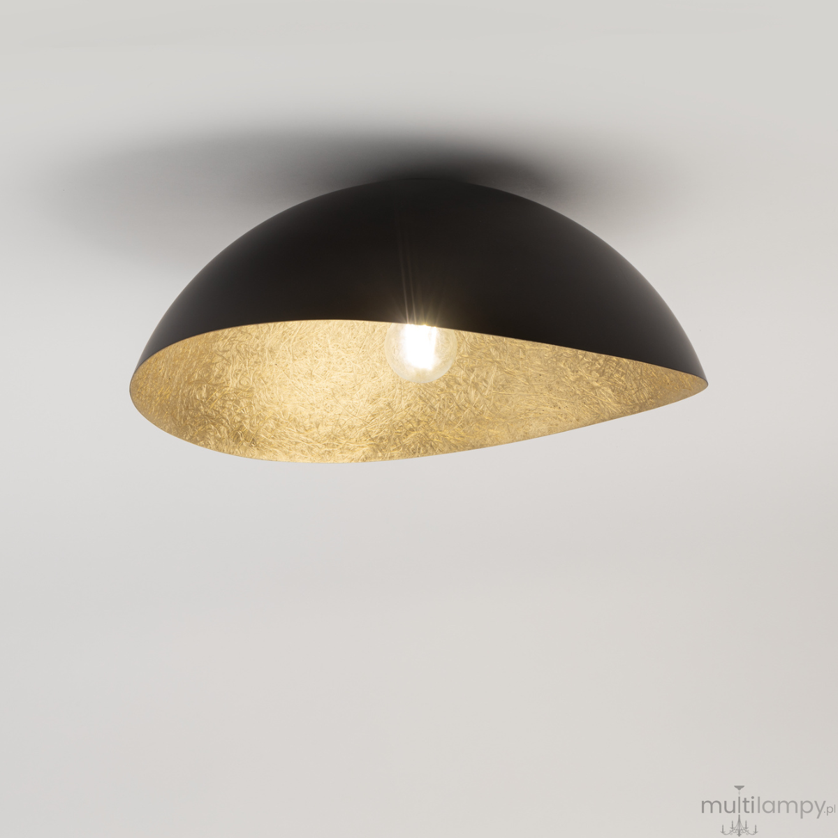 Lampa sufitowa Solaris S w kolorze czarnym z złotym wnętrzem, w kształcie półkuli. Zawiera jedno źródło światła, zawieszona pod kątem, na jednolitym tle. Wykończenie metaliczne, z wyraźnym podziałem kolorów.