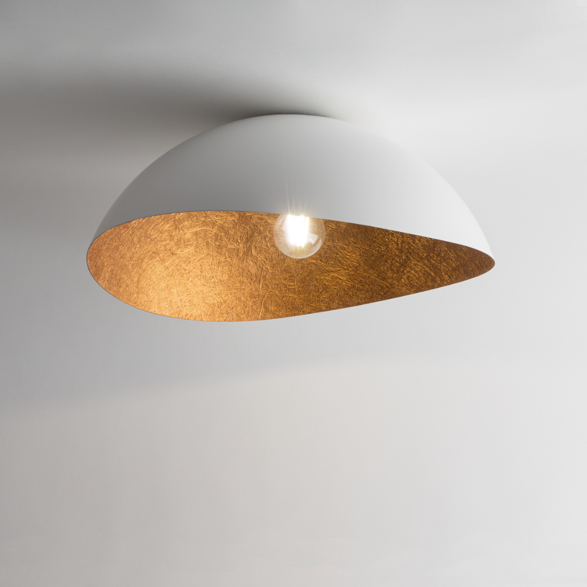 Lampa sufitowa Solaris S w kolorze białym z miedzianym wnętrzem, o półkulistym kształcie. Widoczna żarówka, umieszczona centralnie. Ujęcie z dołu, podkreślające kontrast kolorów i teksturę. Idealna do nowoczesnych wnętrz.