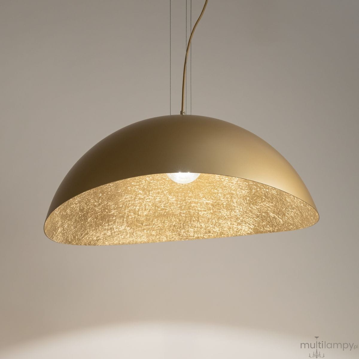 Lampa wisząca Solaris XL 1-punktowa w kolorze złotym, o półkolistym kształcie. Posiada matowe wykończenie zewnętrzne oraz wewnętrzną, teksturowaną powierzchnię, która rozprasza światło. Zawieszona na cienkich linkach, idealna do nowoczesnych wnętrz.