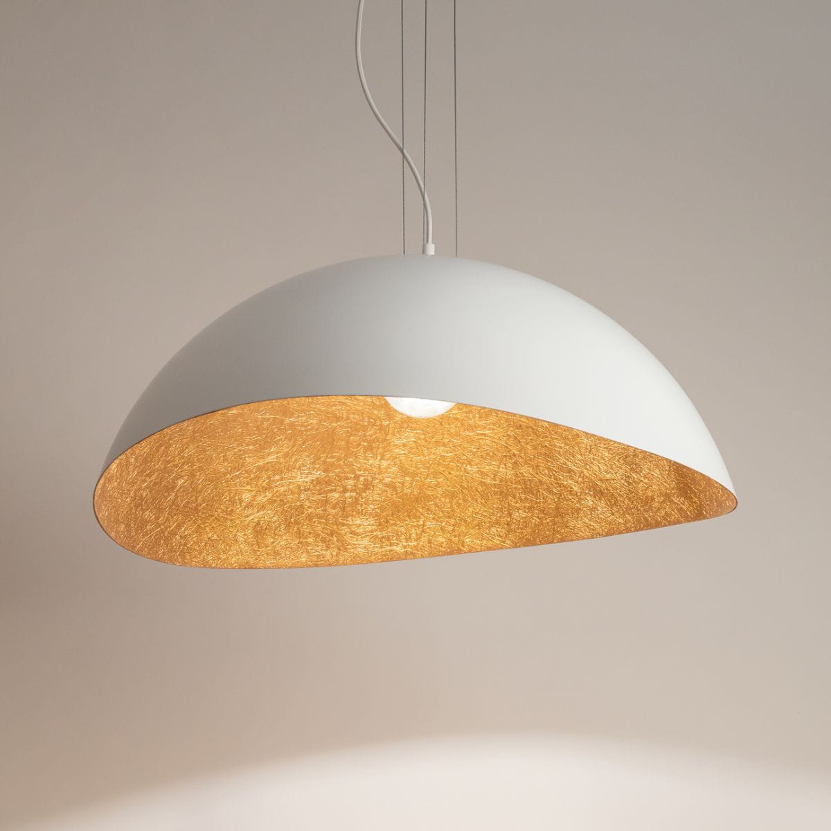 Lampa wisząca Solaris L, 1-punktowa, w kolorze białym z miedzianym wnętrzem. Kształt półkulisty, zawieszona na cienkim przewodzie. Wnętrze lampa ma teksturę, która odbija światło, tworząc ciepłą atmosferę. Tło jasne, jednolite.