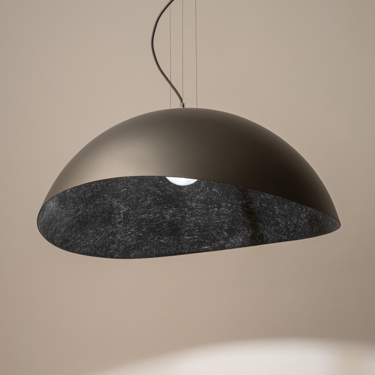 Lampa wisząca Solaris XL, 1-punktowa, o półkulistym kształcie. Wykonana z matowego srebra na zewnątrz i czarnego materiału wewnątrz. Zawieszona na cienkich linkach, idealna do nowoczesnych wnętrz.
