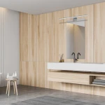 Kinkiet Shine LED IP44 w kolorze chromu, 1-punktowy, zamontowany nad lustrem. Prosty, minimalistyczny design z metalową obudową. Oświetlenie umieszczone na tle drewnianej ściany, w nowoczesnej łazience. Wymiary L80/15W.