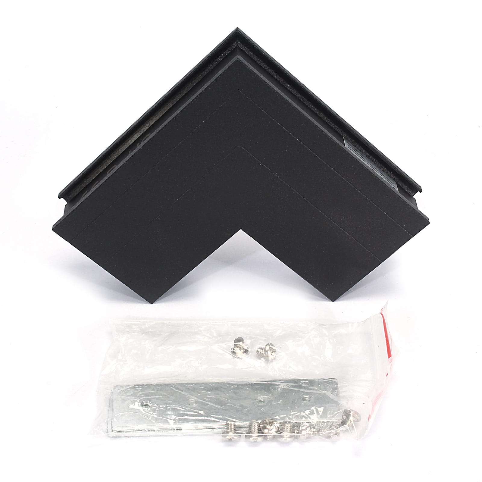 Łącznik kątowy sufit-ściana do szyn magnetycznych w kolorze czarnym, z widocznym kątem prostym. Obok znajduje się opakowanie z metalowymi elementami montażowymi. Produkt leży na białym tle.