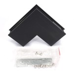 Łącznik kątowy sufit-ściana do szyn magnetycznych w kolorze czarnym, z widocznym kątem prostym. Obok znajduje się opakowanie z metalowymi elementami montażowymi. Produkt leży na białym tle.