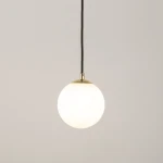 Lampa wisząca Piano w kolorze czarnym z okrągłym, białym kloszem. Zawieszona na czarnym przewodzie, z metalowym wykończeniem w kolorze złotym u góry. Prosty, minimalistyczny design, idealna do nowoczesnych wnętrz.