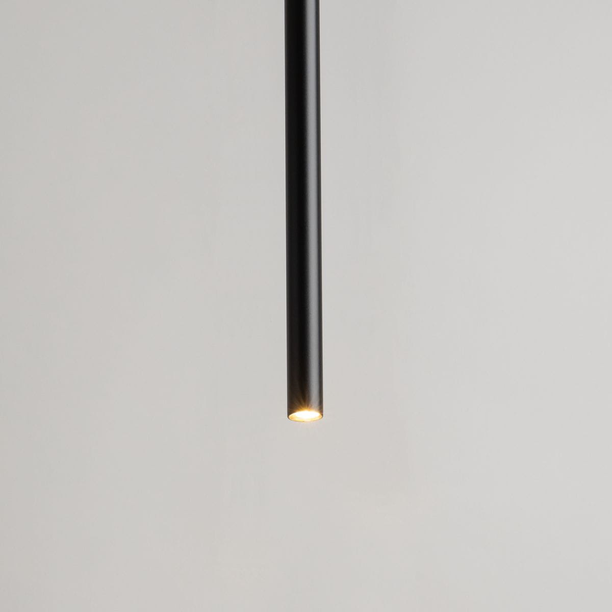 Lampa wisząca Sopel Prosty 5-punktowa w kolorze czarnym. Wąski, cylindryczny kształt z widocznym źródłem światła na końcu. Ujęcie z dołu, na jasnym tle. Idealna do nowoczesnych wnętrz.