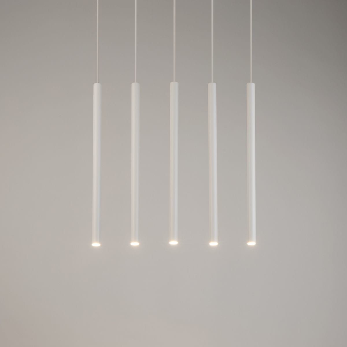 Lampa wisząca Sopel Prosty 5-punktowa w kolorze białym, składająca się z pięciu długich, cylindrycznych elementów. Ułożona w poziomie, z delikatnym światłem na końcach, zawieszona na cienkich linkach w minimalistycznym stylu.