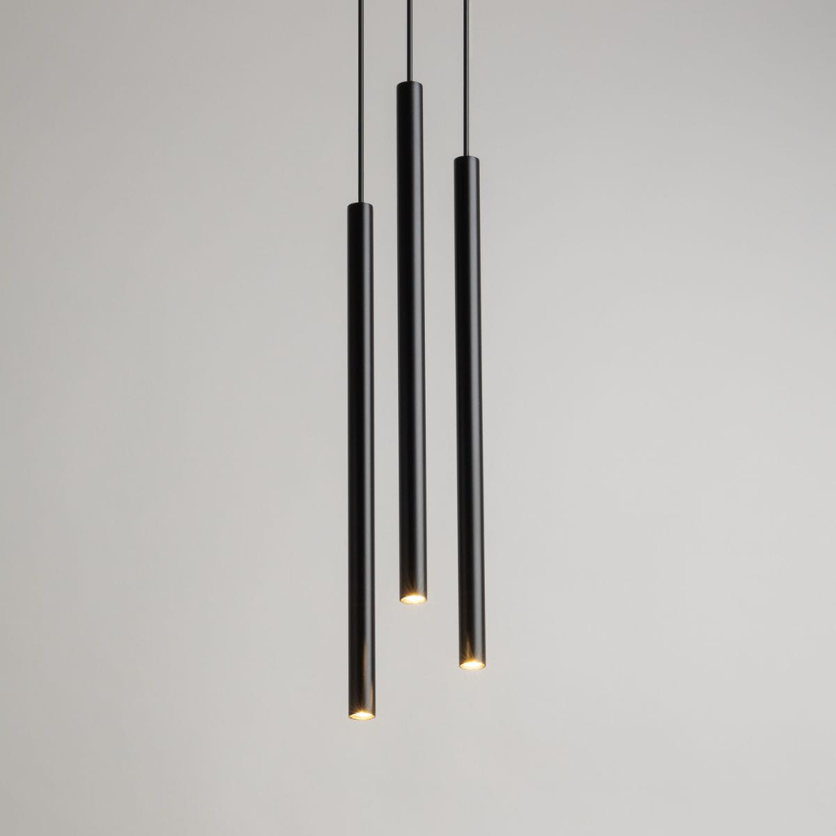 Lampa wisząca Sopel Koło 3-punktowa w kolorze czarnym. Składa się z trzech cylindrycznych ramion, zawieszonych na cienkich linkach. Każde ramie zakończone jest źródłem światła, na tle jasnej ściany.