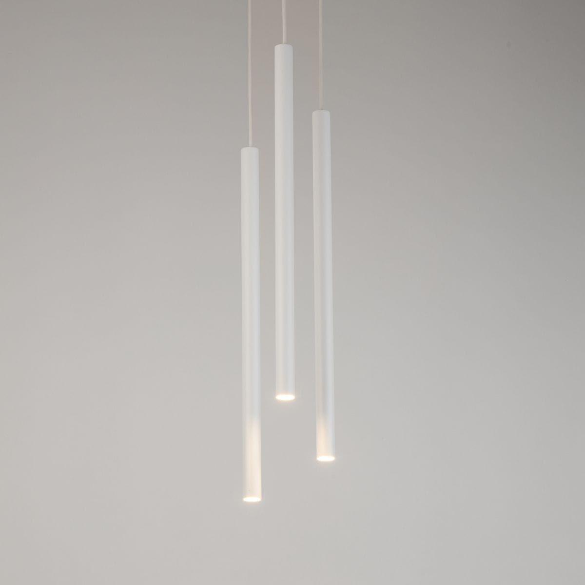 Biała lampa wisząca Sopel Koło z trzema cylindrycznymi punktami świetlnymi. Ujęcie frontalne, zawieszona na cienkich linkach, minimalistyczny design. Tło jasne, jednolite.