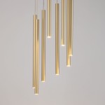 Lampa wisząca Sopel Koło, 8-punktowa, z ośmioma złotymi, cylindrycznymi elementami o różnej długości, emitującymi światło. Produkt zawieszony na cienkich linkach, na jasnym tle, prezentujący nowoczesny design.