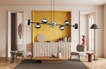 Lampa wisząca Rossi 8-punktowa w kolorze czarnym, z okrągłymi kloszami z przezroczystego materiału, zawieszona poziomo nad drewnianym stolikiem. Tło w odcieniu żółtym, nowoczesne wnętrze z meblami w stonowanych kolorach.