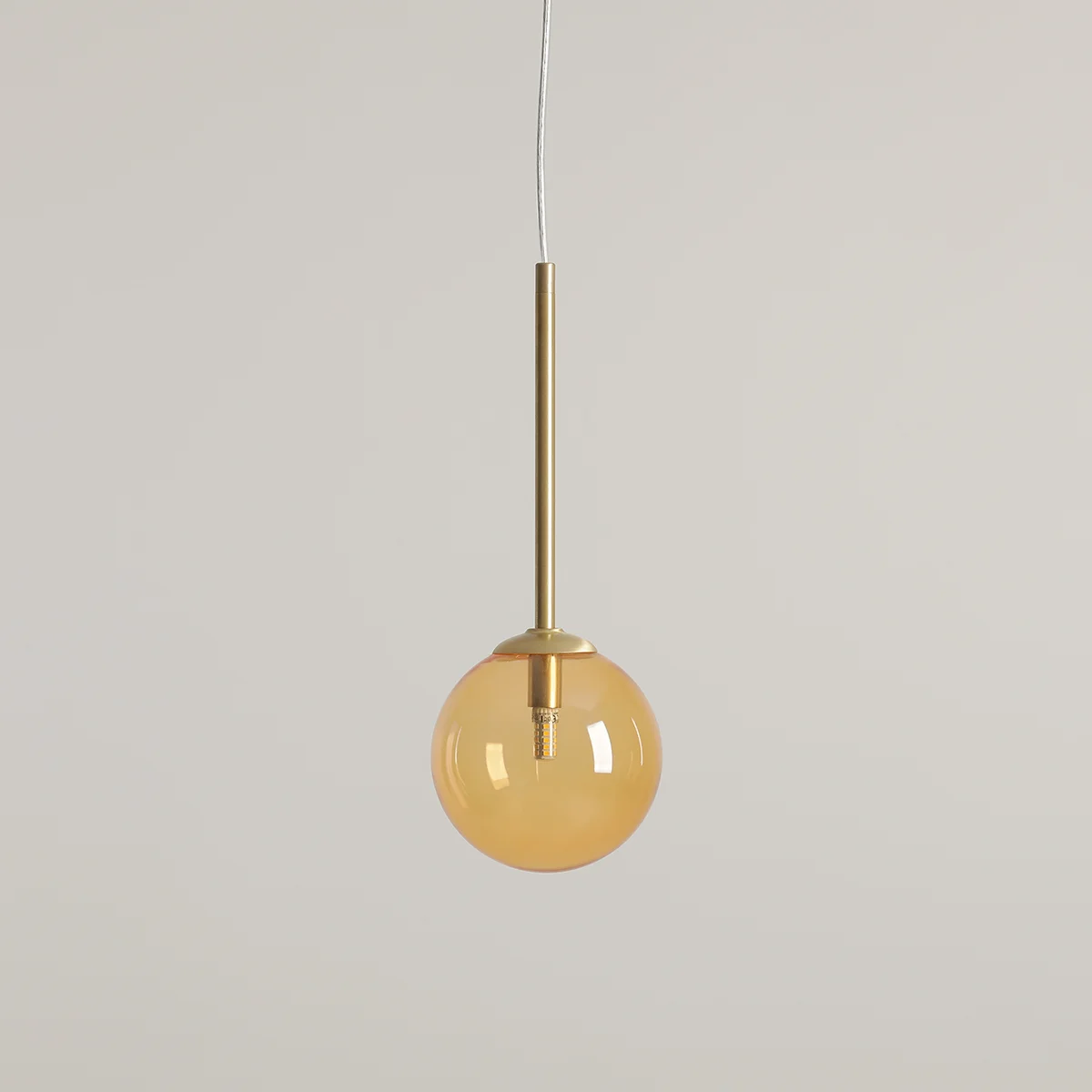 Lampa wisząca Bosso D14 z mosiężnym uchwytem i okrągłym kloszem w kolorze pomarańczowym. Ujęcie z przodu, zawieszona na cienkim przewodzie. Przeznaczona do jednej żarówki G9. Tło jasne i jednolite.