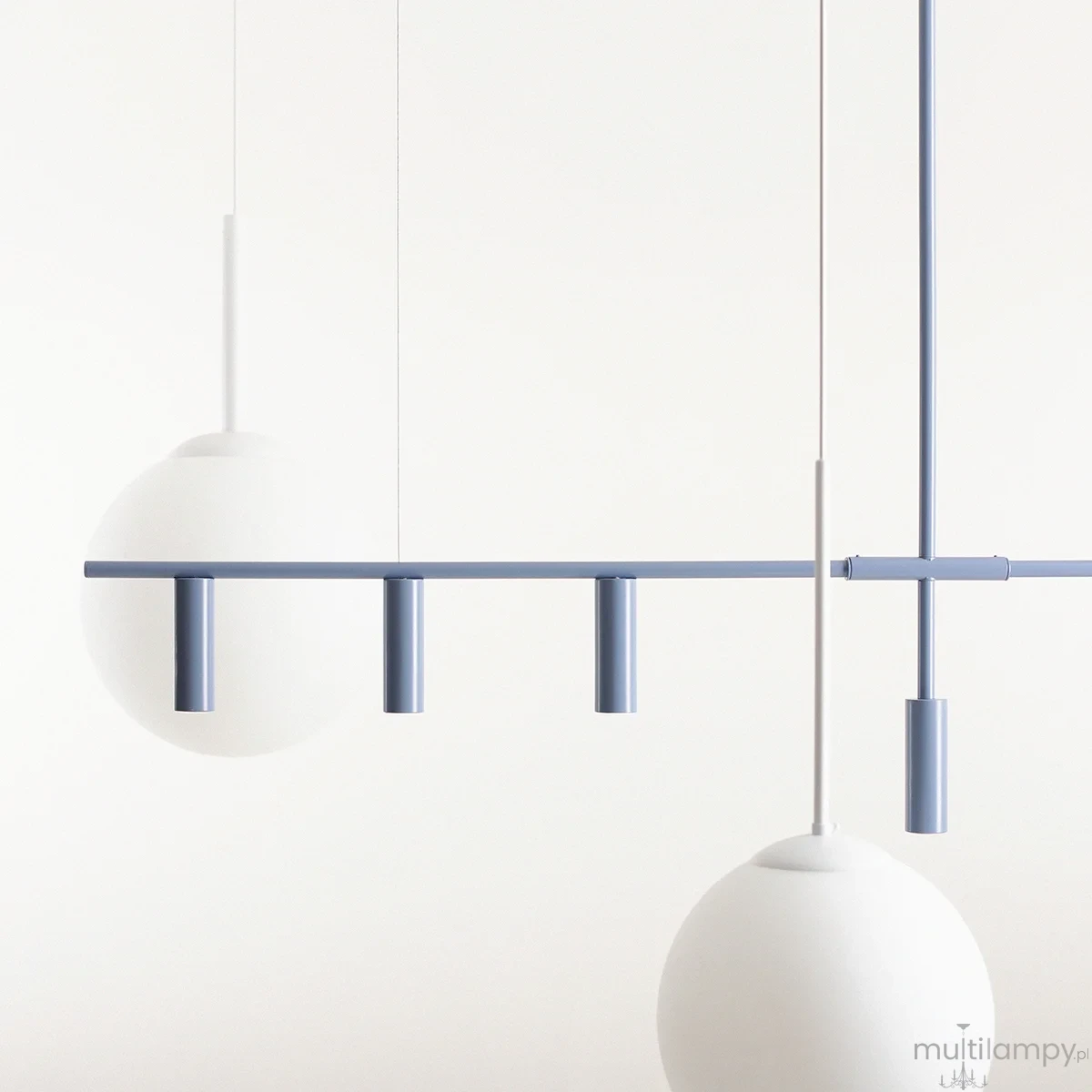 Lampa wisząca Trevo 6-punktowa w kolorze niebieskim. Składa się z prostokątnej belki z trzema cylindrycznymi punktami świetlnymi oraz dwiema okrągłymi, matowymi kloszami. Całość zawieszona na cienkich linkach, na jasnym tle.