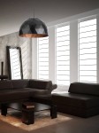 Lampa wisząca Diament D50 w kolorze czarnym z miedzianym wnętrzem, o kształcie półkulistym z wyraźnym, diamentowym wzorem. Zawieszona w nowoczesnym wnętrzu z ciemnymi meblami, na tle dużych okien.