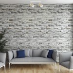 Lampa sufitowa Anillo (spot) 2xGU10 w kolorze białym, zamontowana na suficie, z dwoma regulowanymi źródłami światła. Tło stanowi ściana z kamienia, a przedmiot znajduje się nad szarym sofą z niebieskimi poduszkami.