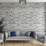 Lampa sufitowa Anillo, czarna, z dwoma spotami GU10. Ujęcie z góry na zamontowaną lampę na tle kamiennej ściany. W tle widoczna szara sofa z niebieskimi poduszkami oraz roślina.