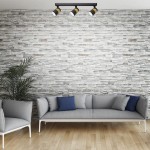 Lampa sufitowa Anillo (spot) 3xGU10 w kolorze czarnym, zamontowana na suficie, z trzema reflektorami kierunkowymi. Tło stanowi kamienna ściana, a w aranżacji widoczne są szare meble z niebieskimi poduszkami.